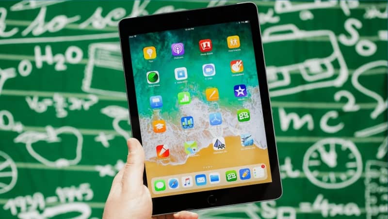 iPad kädessä ja matemaattisten kaavojen tausta