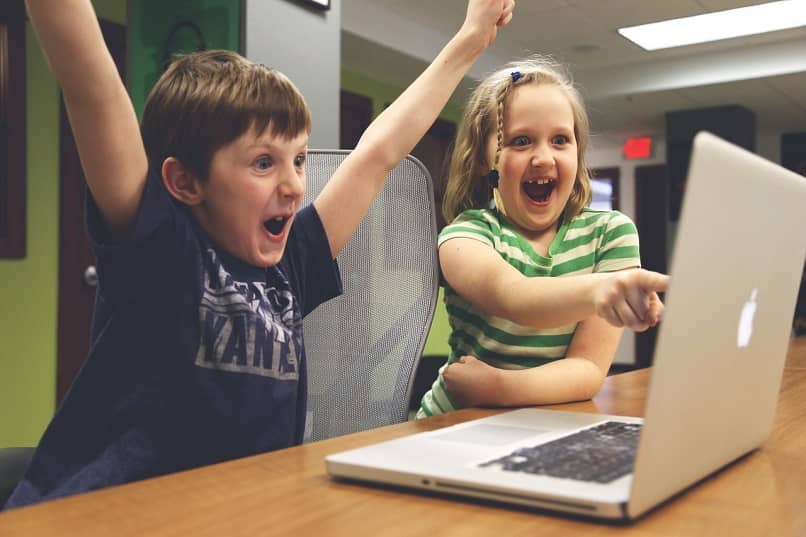 onnelliset lapset käyttävät kannettavaa tietokonetta