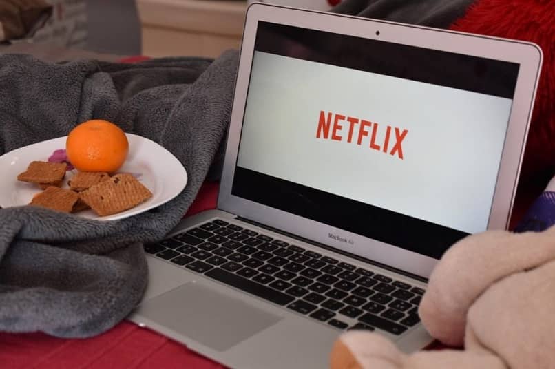 kannettava tietokone netflixissä, jonka vieressä ruokalautanen