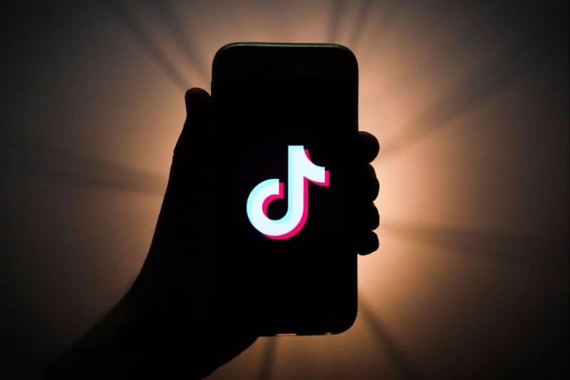 Matkapuhelin Tik Tok kädessä tumma tausta