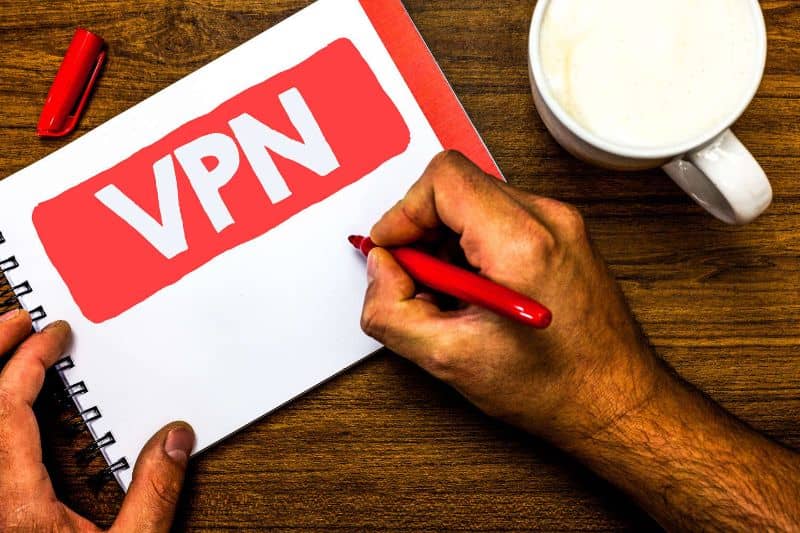 kädet, joilla on VPN-muistikirja kahvilan vieressä