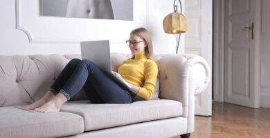 mujer sonriendo sofa laptop