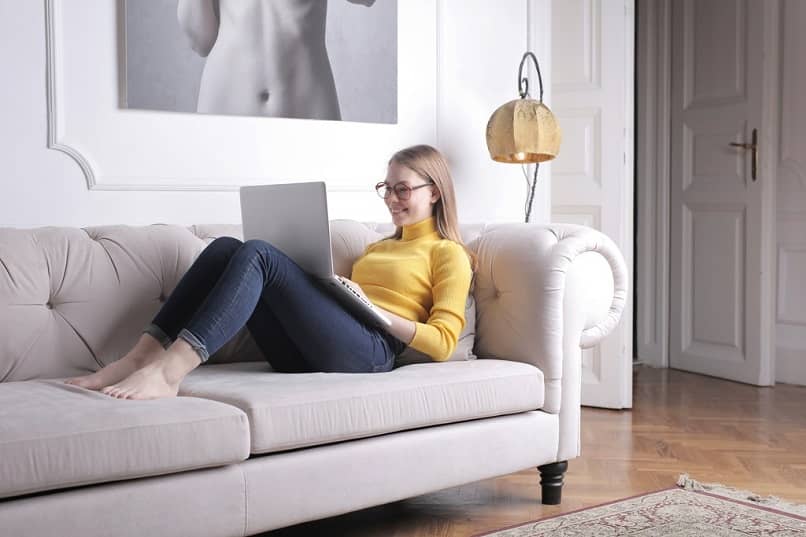 mujer sonriendo sofa laptop