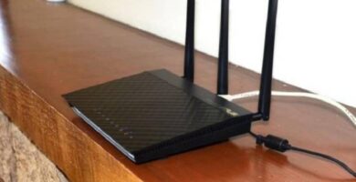 router negro tres antenas sobre repisa madera