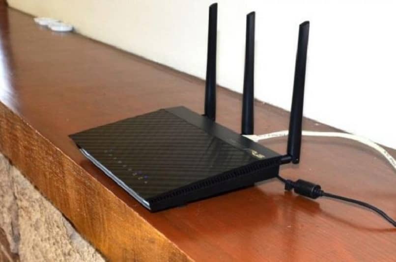 router negro tres antenas sobre repisa madera