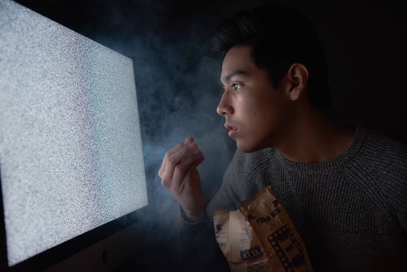 mies syö popcornia katsomassa televisiota