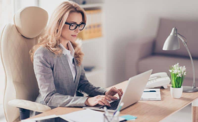 mujer sentada manejando laptop