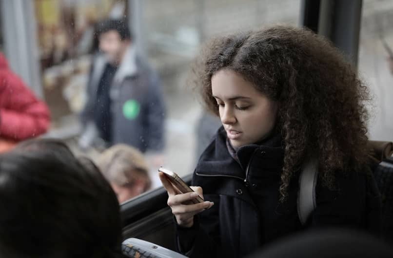 tyttö bussissa matkapuhelimen avulla