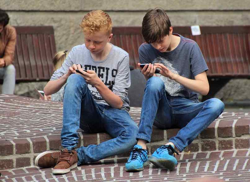 pojat leikkivät puhelimella kadulla